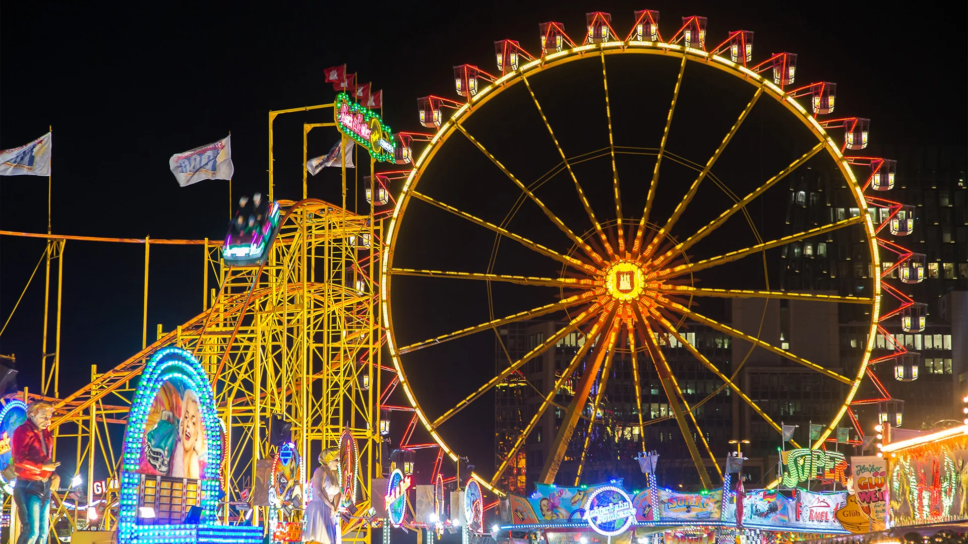 Beleuchtetes Riesenrad und Fahrgeschäfte auf dem Hamburger Dom bei Nacht